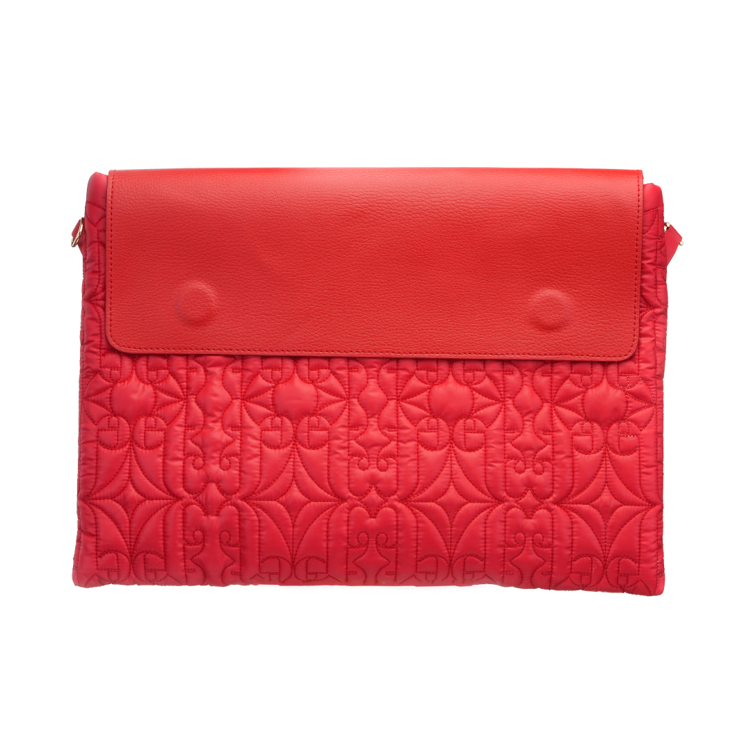 Red quilted laptop sleeve with flap closure, carried by a woman in a polka dot dress for a chic modern look.
