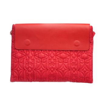 Red quilted laptop sleeve with flap closure, carried by a woman in a polka dot dress for a chic modern look.